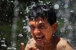 A boy cools himself at a fountain of a park in Athens, Greece. - REU-GREECE_1