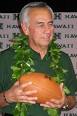 Norm Chow wearing maile lei and holding a football - chow