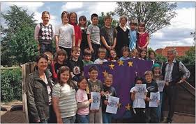 Stolz präsentieren die Schülerinnen und Schüler die Europa-Flagge für die Boy-Lornsen-Grundschule, eingerahmt von Anke Nanz, Klassenlehrerin der 3.