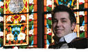 Gabriel Hada in front of a stained glass window - photo by Michael Richeson - faith-stained-glass