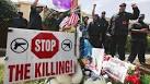 Members of the New Black Panther Party rally next to a memorial of Trayvon