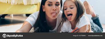 mother daughter tongue|Mother and daughter with mobile phone sticking out tongue while listening  music through headphones at home Stock Photo - Alamy