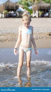beach little garl|Portrait of little girl sitting on the beach with legs under sand stock  photo