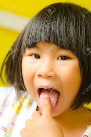 tongue girl|Close-up portrait of girl sticking out tongue at park stock photo